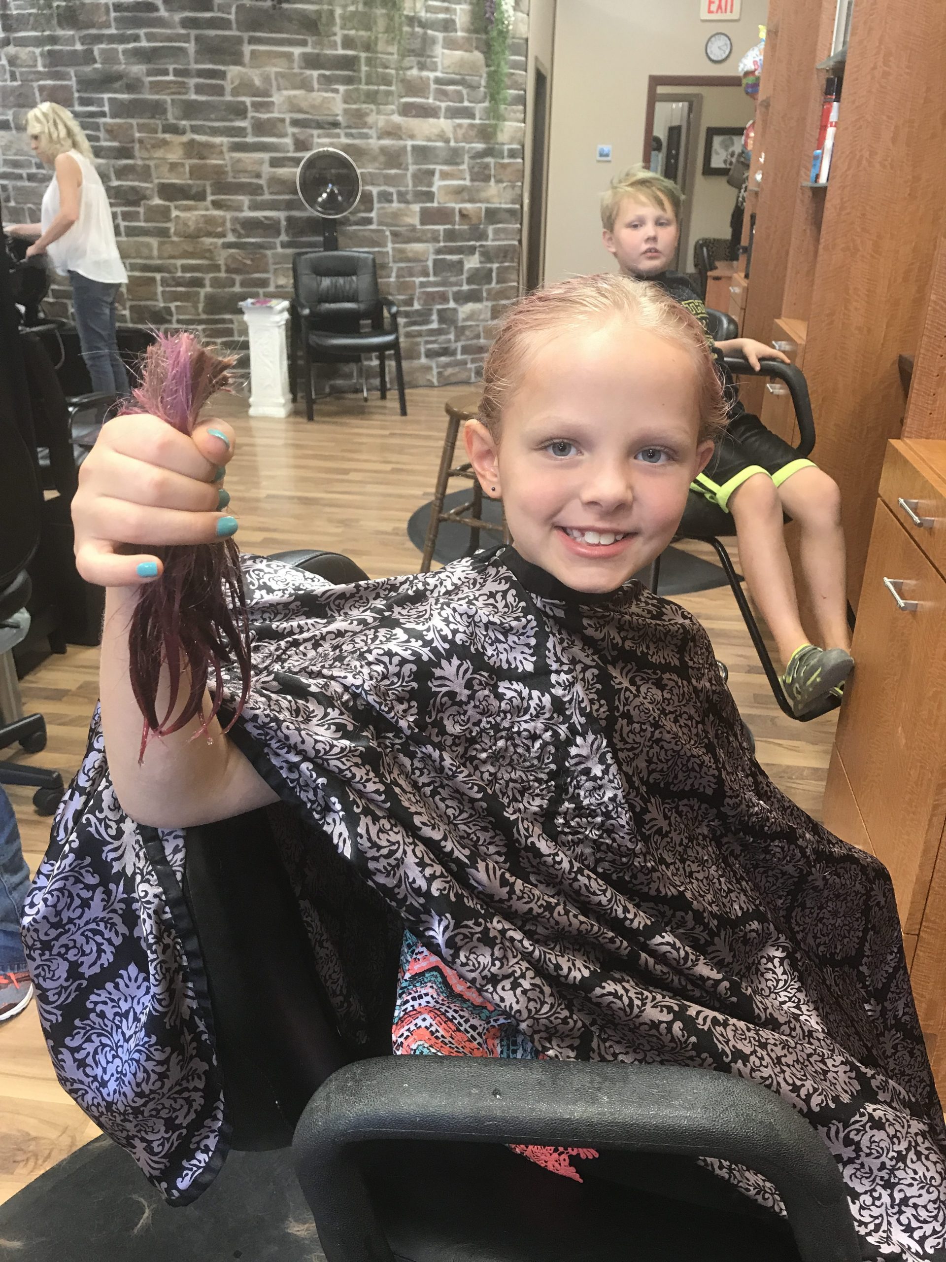kids in salon, girl holding cut off ponytail